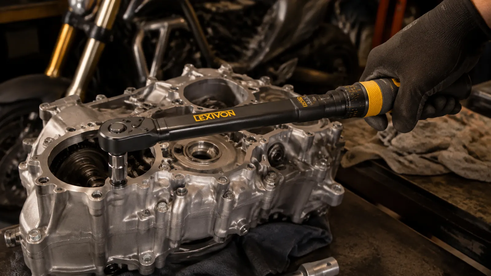 A gloved hand pulling a click torque wrench to the point where it clicks over a bolt on an engine case