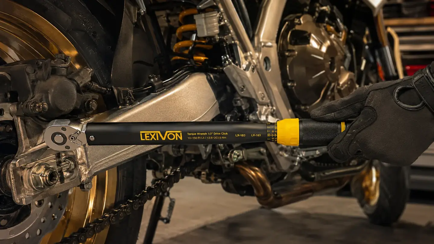 A gloved hand using a 1/2-inch drive torque wrench on a bolt in a motorcycle engine swingarm area